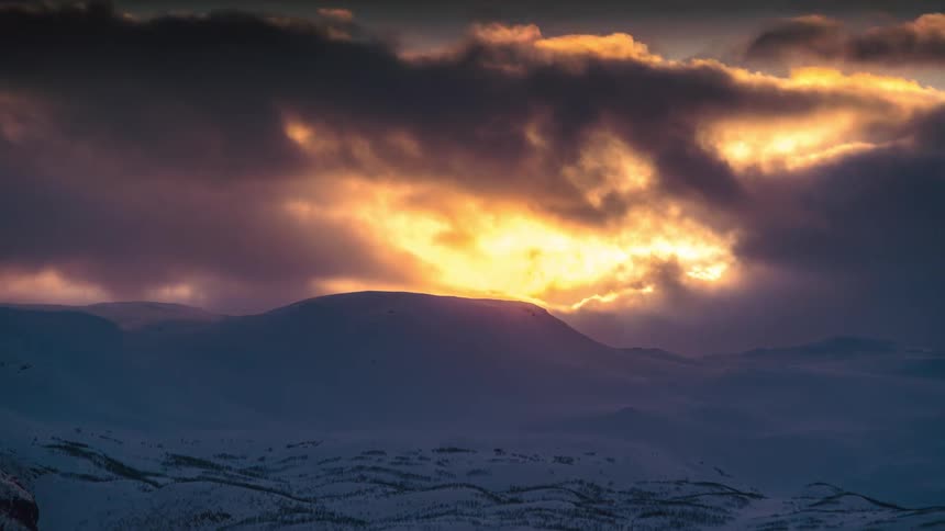 Panorama of the setting sun amidst snowcovered mountains in timelapse