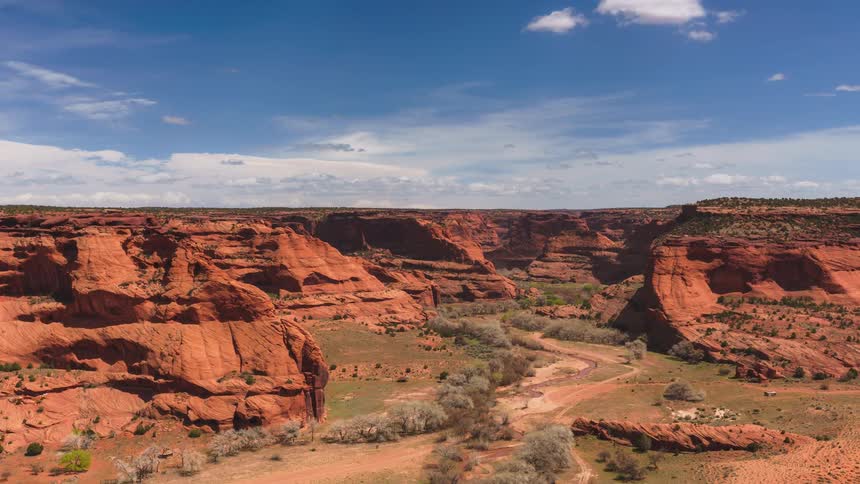 Vehicles driving along dirt road through canyon terrain on a cloudy day pass in opposite directions