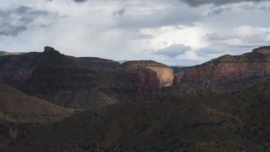 A canyon with layered rock formations under a cloudy sky