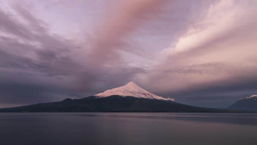 A time lapse of a sunset over a mountain with snow on the top