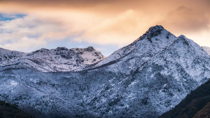 Heavy clouds move over a snowy mountain range