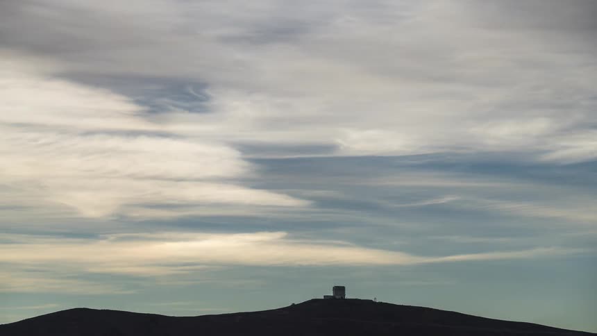 A telescope with a sun halo in the clouds moving by