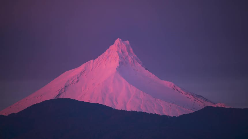 vibrant sunset colors moving over a distant icy mountain peak