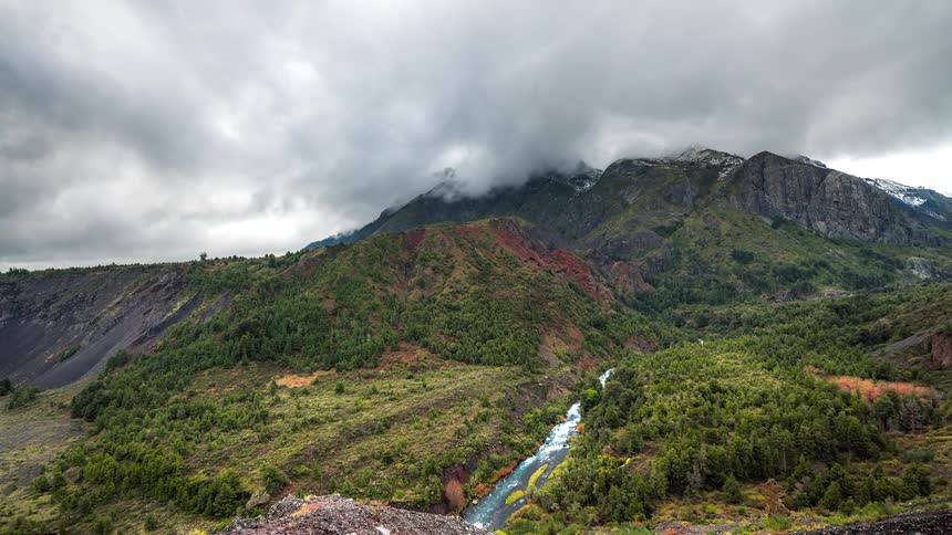 Low lying clouds flow over mountains and flowing river