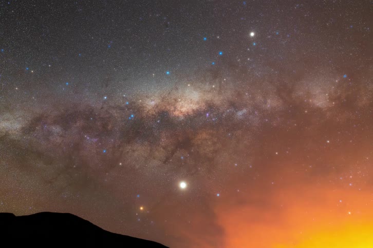 Milky way fades from sky as night turns to day over a mountain in the desert