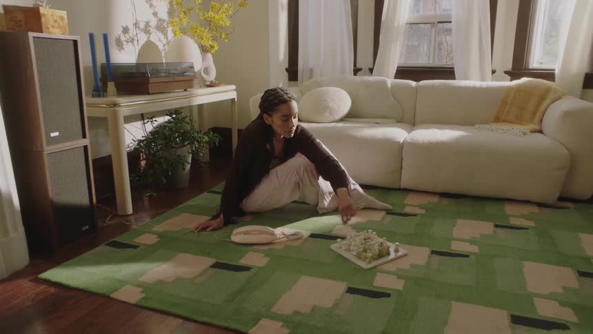 Young Woman sitting on the living room floor playing chess alone