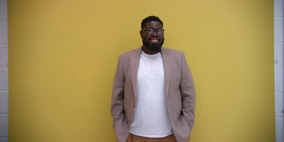Model in a studio with a yellow background wearing a blazer smiling