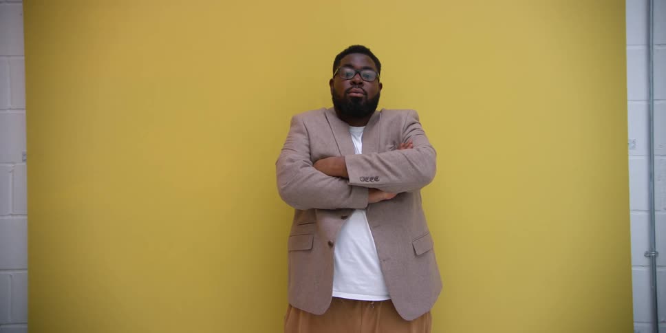 Man modeling with a blazer against a yellow background