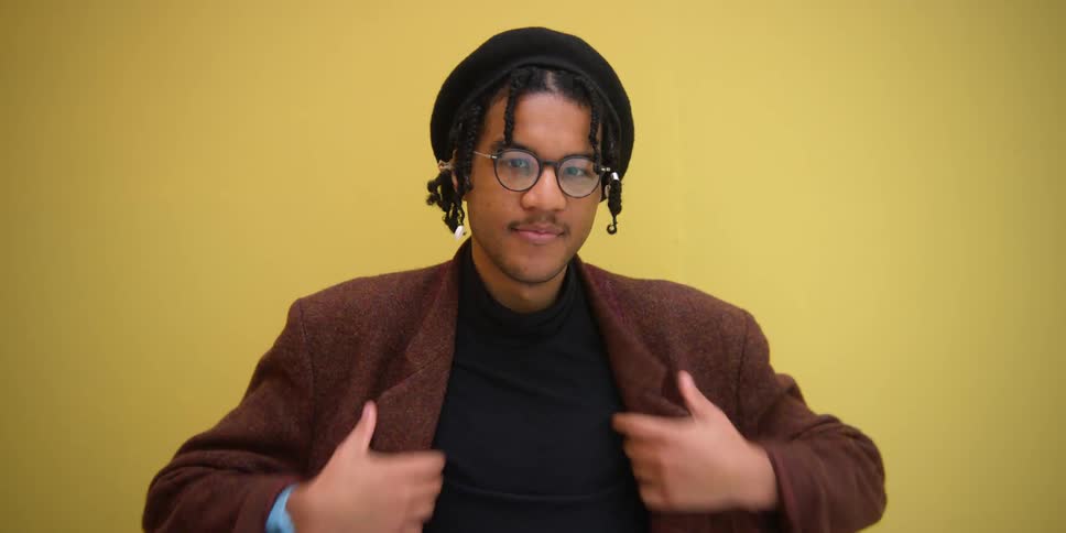 A young black man adjusts his clothing and smiles