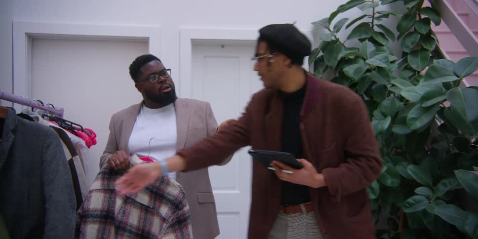 Two men choose clothing from a rack