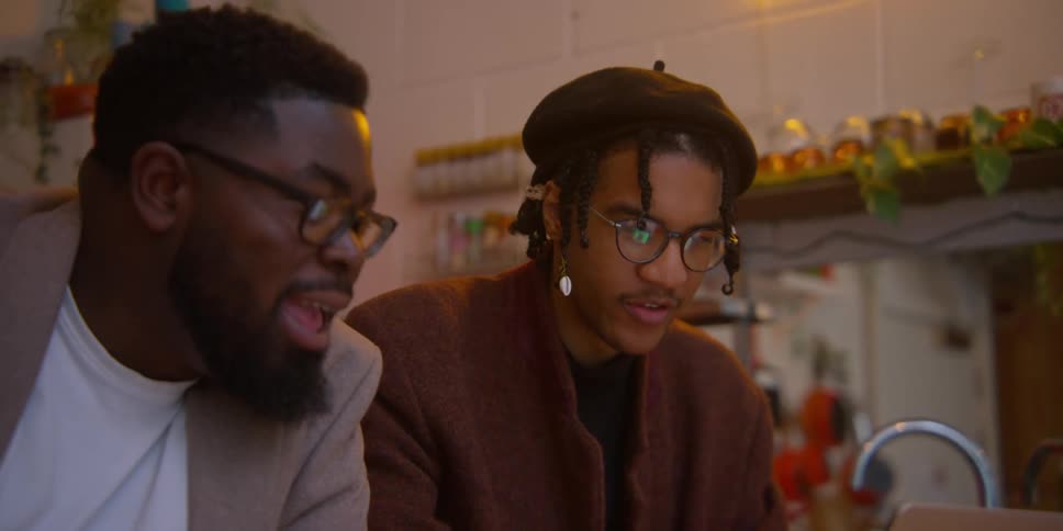 Men talking in the kitchen looking at the computer screen