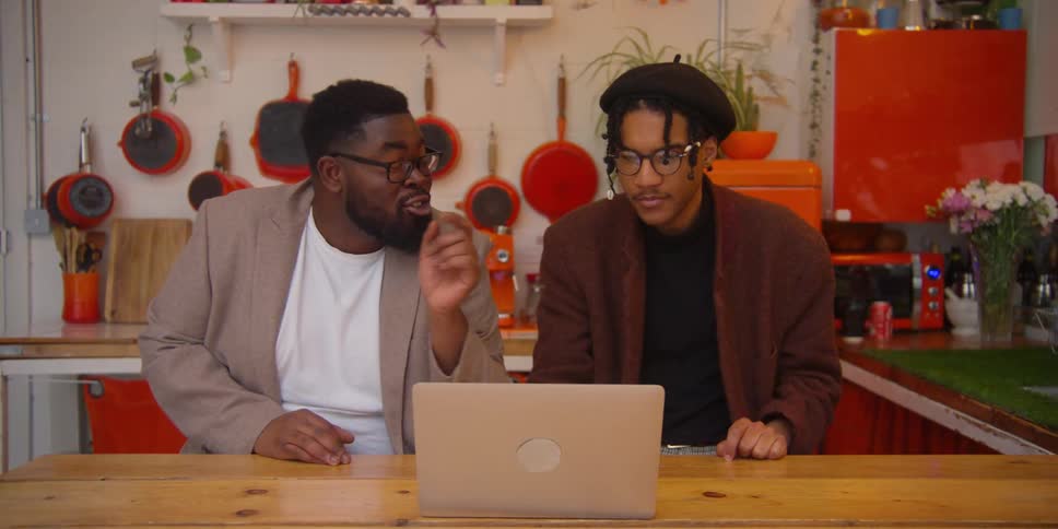 Two black men talking while staring at a laptop