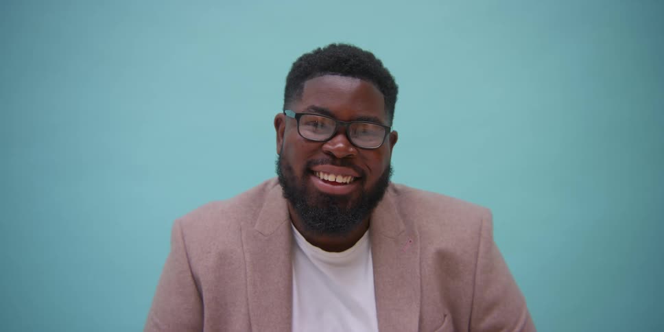 A black man smiling in front of a board