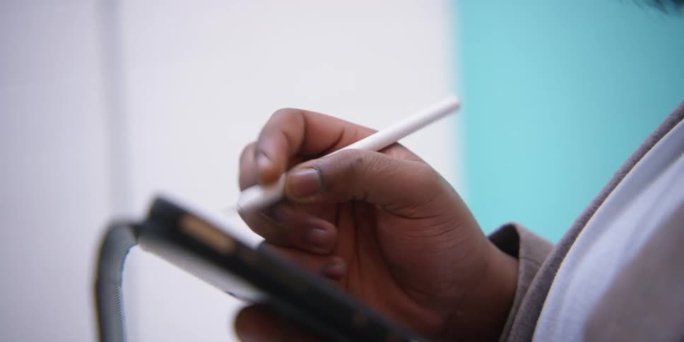 A black man writes on a tablet while teaching