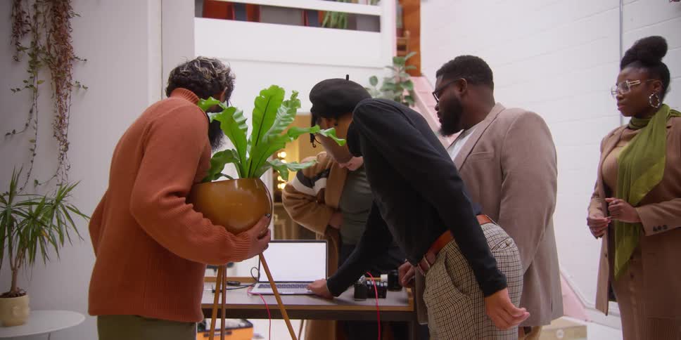 A group of people around a table looking at photos on a laptop