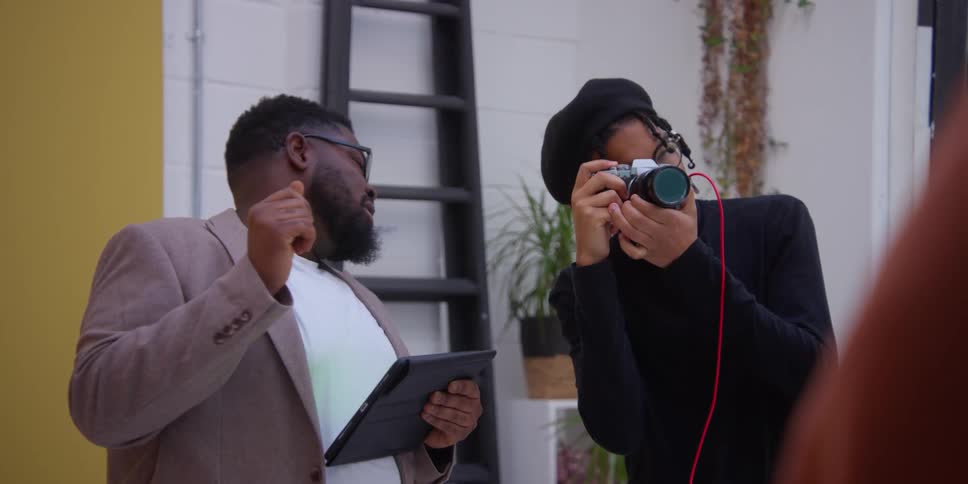 A person holding a tablet and photographer with a camera taking pictures of models