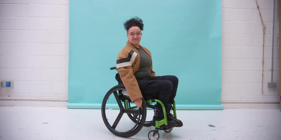 Wheelchair model rolling into frame smiling and posing in a studio