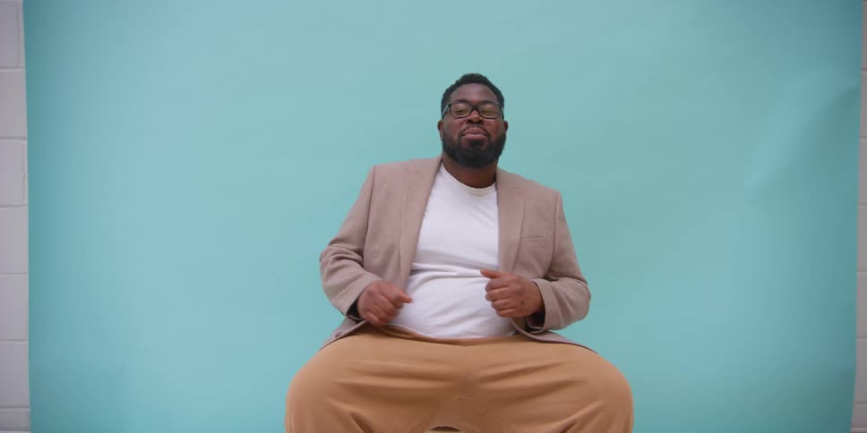 Model man wearing a blazer sitting on a blue background studio