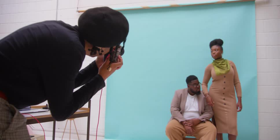 A black man photographs a black man and black woman