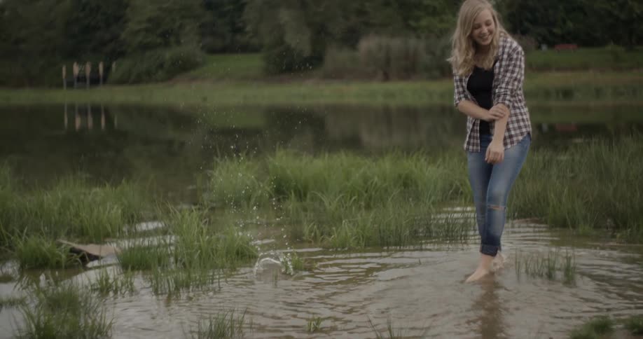 A woman smiles as she stands in the water by a lake