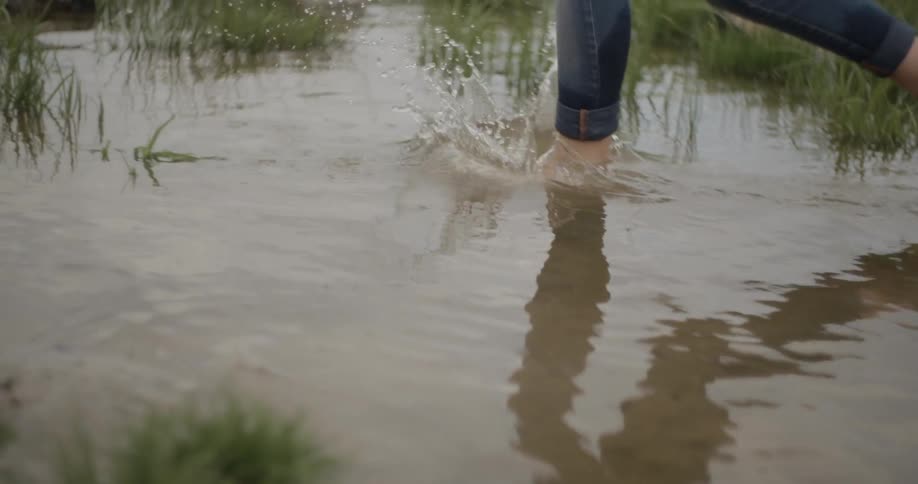 A woman is splashing water in a small pond