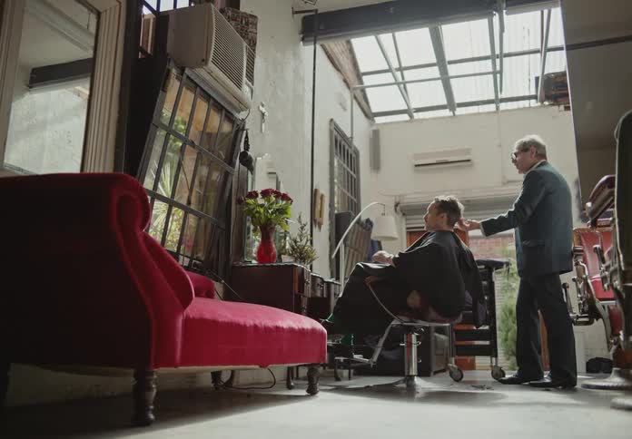 A barber styles a clients hair in a barbershop
