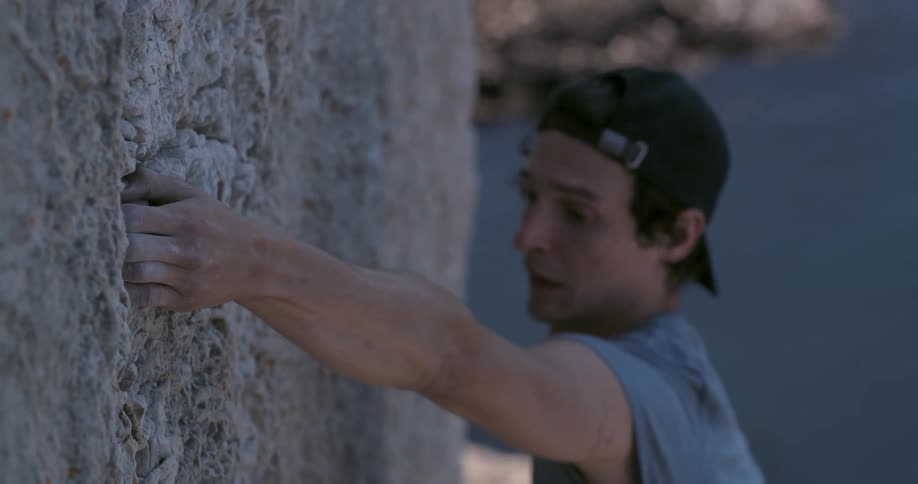 Man with facial expression of concentration and tiredness leaning on a mountain wall climbing