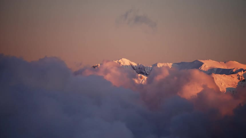 Heavy clouds partially obscure a snow covered mountain range