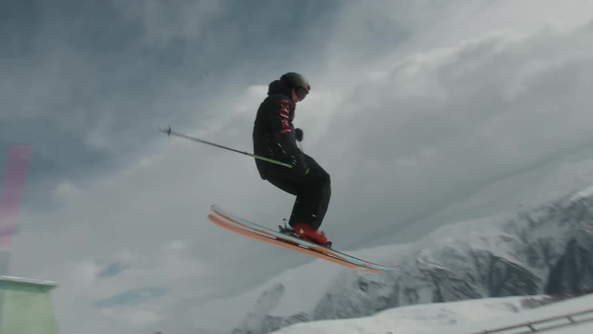 A person skiing makes a jump and lands on the snow crouching