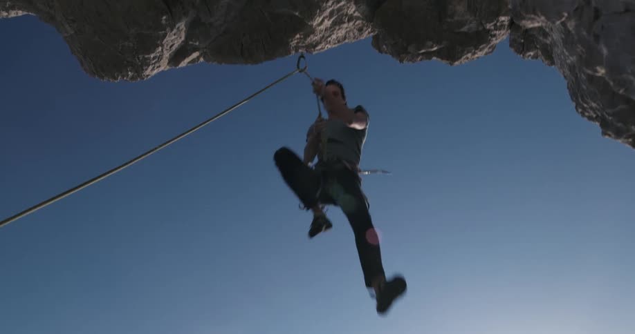 A man rappels down a steep cliff