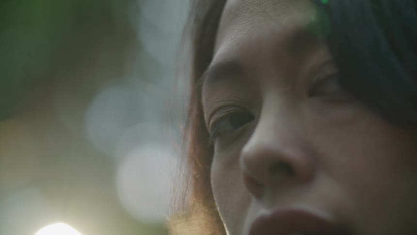 Close up of the face of a young woman in front of the sun