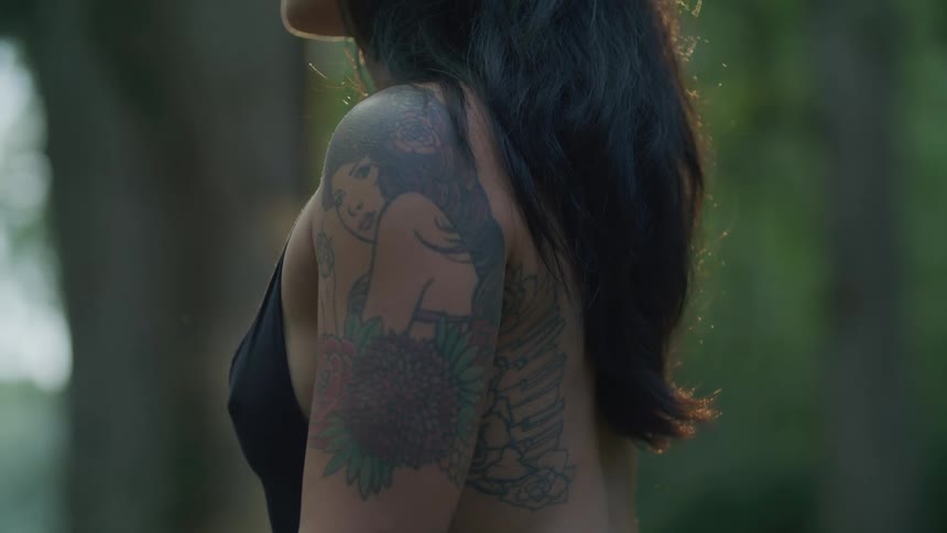 Closeup of the side and arm of a woman with a tattooed womans face