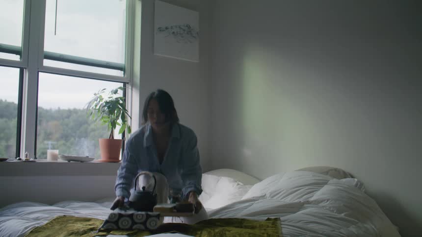 A young woman carries a tray with tea to bed