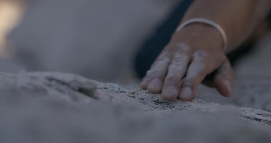 Closeup of a persons hand that was holding on to a rocky wall and ends up letting go of the hand and falling