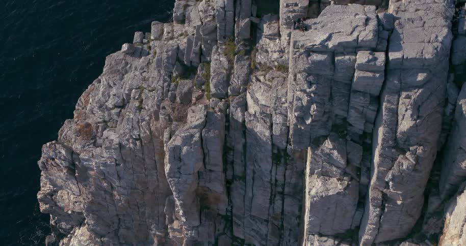Man climbing a mountain wall half seaside cliffs