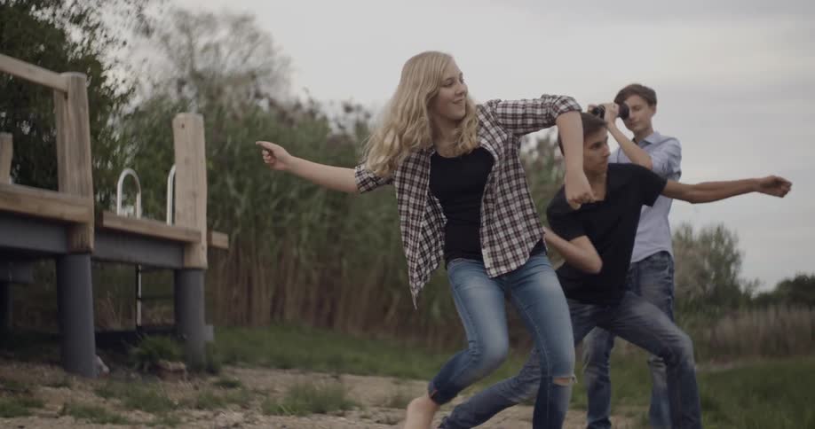 Two young people throw rocks as another films them