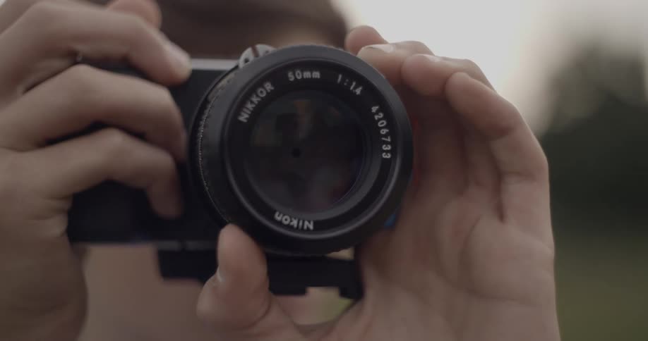 A man looks through a camera lens