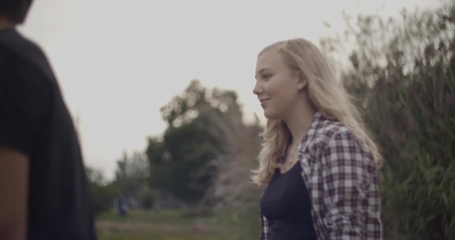 A blonde woman in a plaid shirt smiles near a man
