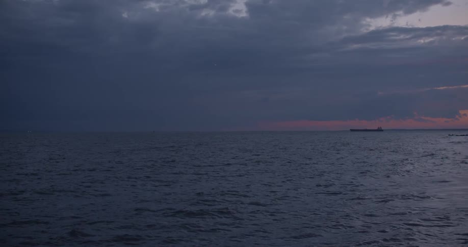 Waves flow in the ocean as a ship is in the distance