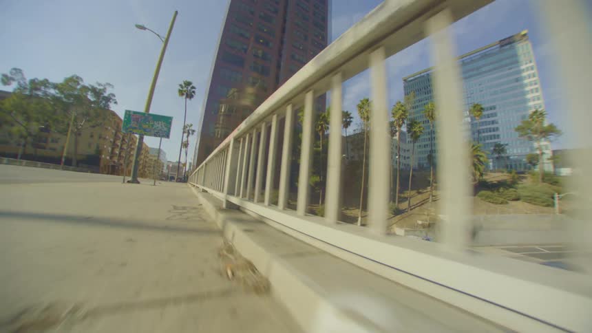 A sidewalk with a hand guard and underneath a highway with many cars passing by