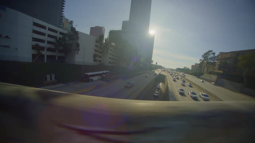 Bridge overlooks busy highway and buildings on a sunny day