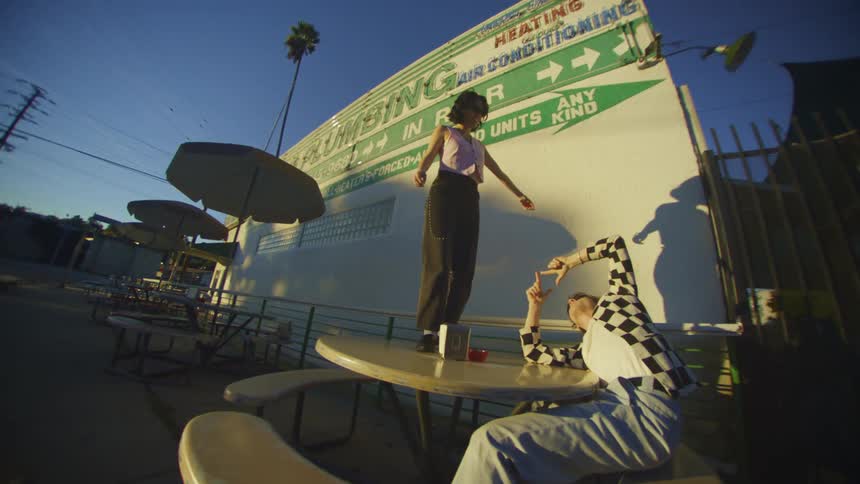 A girl dances happily on the table while her friend films it with his cell phone
