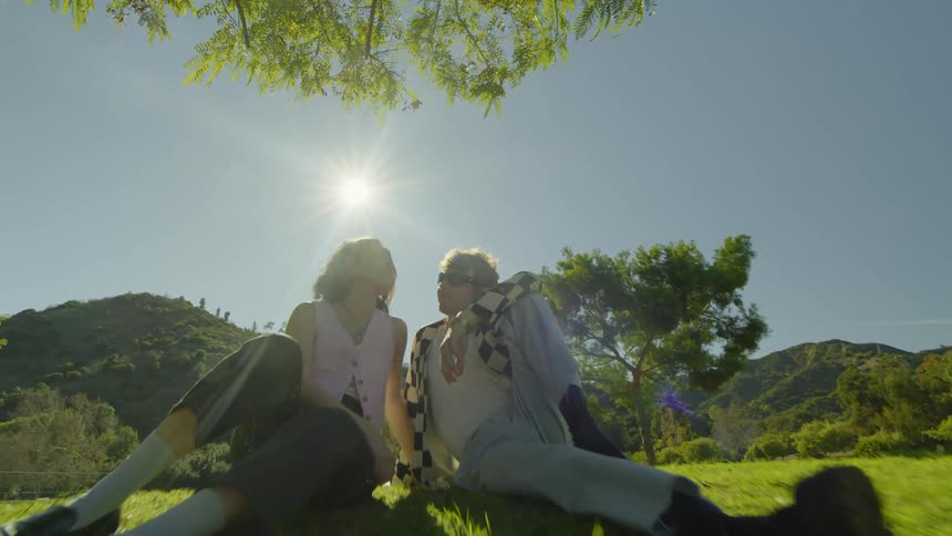 A man and woman lean against each other in the park