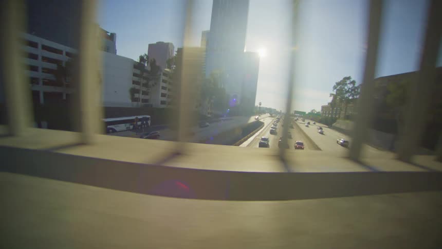 Highway traffic visible through rails passes under bridge on sunny day