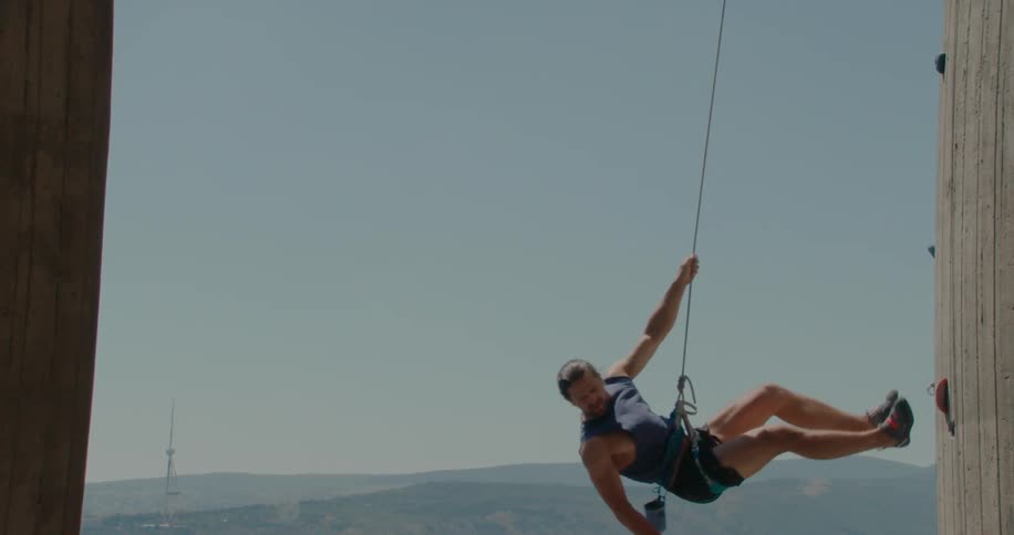 Man descending with a safety rope from a climbing wall