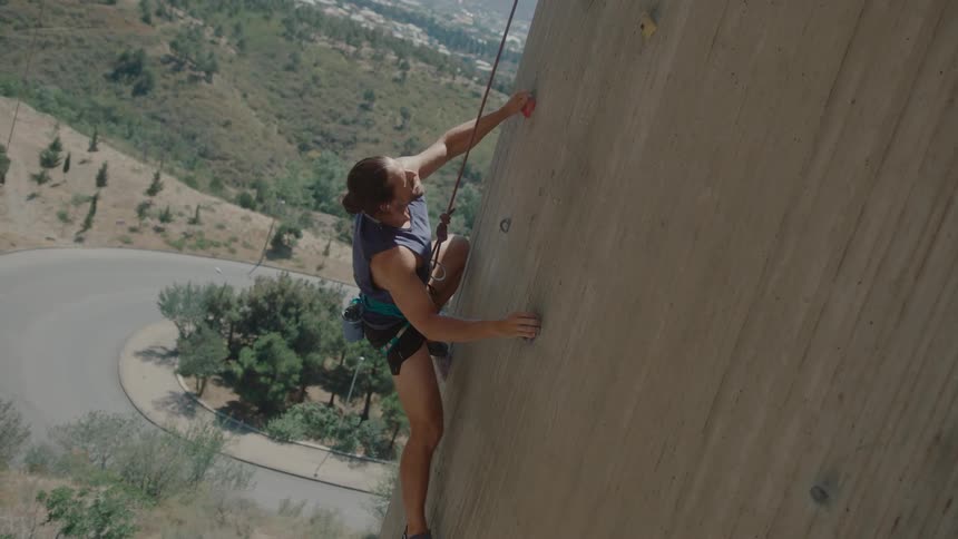Man climbing a wall with a safety harness
