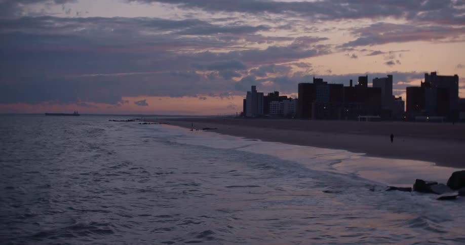 Ocean waves splashing up on the beach next to a city