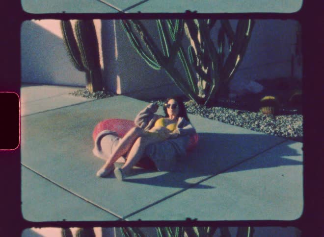 Woman sunbathes on sidewalk near house