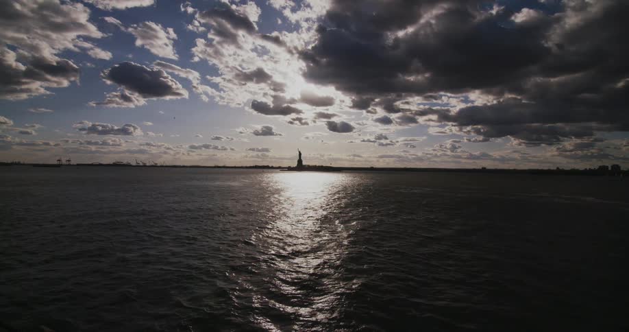 The sun shines and glistens in front of the statue of liberty