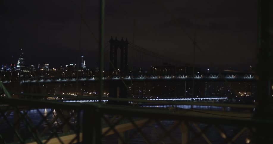 A view of a bridge illuminated by city lights at night